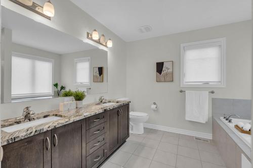a white bathroom with two sinks and a toilet at Luxurious and Beautiful, Ottawa in Ottawa