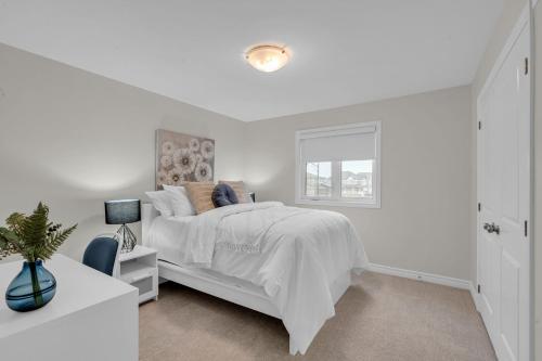 a white bedroom with a bed and a window at Luxurious and Beautiful House in Ottawa