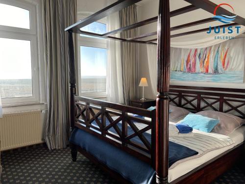 een slaapkamer met een hemelbed en 2 ramen bij Pension Marie Luise 255 - Zimmer Kammmuschel in Juist