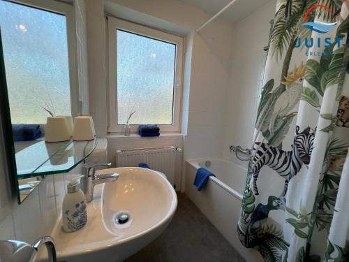 a bathroom with a sink and a shower curtain at Pension Marie Luise 257 - Kombi-Zimmer Auster in Juist