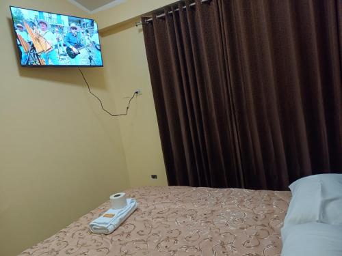 a bedroom with a bed with a tv on the wall at HOSPEDAJE DONA in Ayacucho