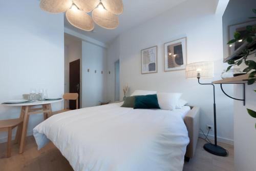 une chambre avec un lit blanc et une table dans l'établissement Le Cachat - hyper centre - wifi gratuit, à Évian-les-Bains
