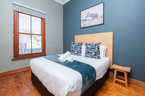 a bedroom with a large bed with blue walls and a window at Elegant Home Nestled in a Serene Suburban Setting in Cape Town