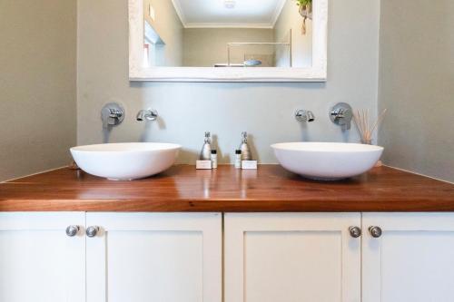 two white sinks on a wooden counter in a bathroom at Elegant Home Nestled in a Serene Suburban Setting in Cape Town