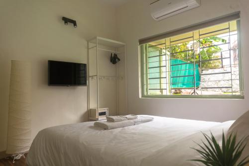 sypialnia z białym łóżkiem i oknem w obiekcie SOUZAGAD VERDE w mieście Panvel