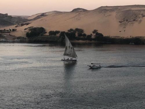 um pequeno barco à vela em um grande corpo de água em Nubian King em Aswan