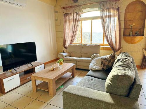 un soggiorno con un divano e una TV di Ortensia a Taʼ Bullara