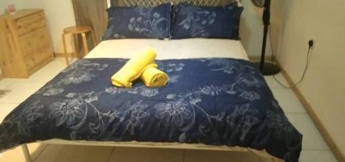 1 cama con 2 almohadas amarillas y manta azul en BaniS Homestay, en Shah Alam