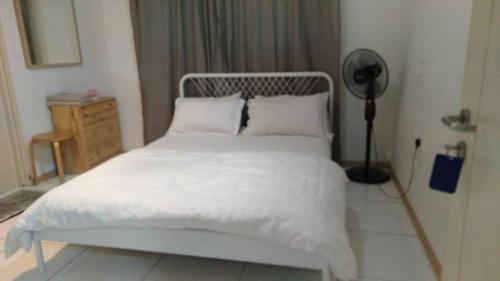 Una cama con sábanas blancas y almohadas en un dormitorio en BaniS Homestay, en Shah Alam