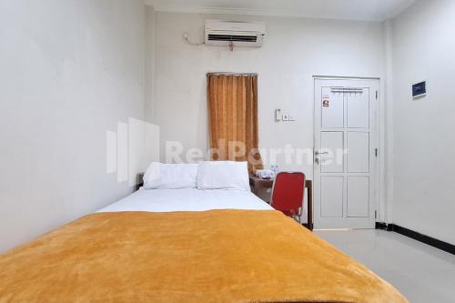 a bedroom with a bed with a yellow blanket on it at De Peppzzz near UGM Yogyakarta RedPartner in Kejayan