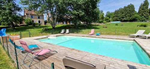 a swimming pool with two chairs and a table at Maison d'hôtes Ourdeaux et Gite Chez Rouchon in Alleyrat