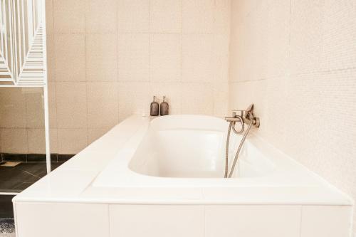 een wit bad in een wit betegelde badkamer bij Appartement T2 avec ascenseur privé in Antananarivo