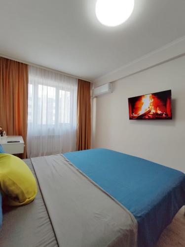 1 dormitorio con 1 cama grande y TV en la pared en Аккуратная 1-комнатная квартира в ЖК Nomad, en Almaty