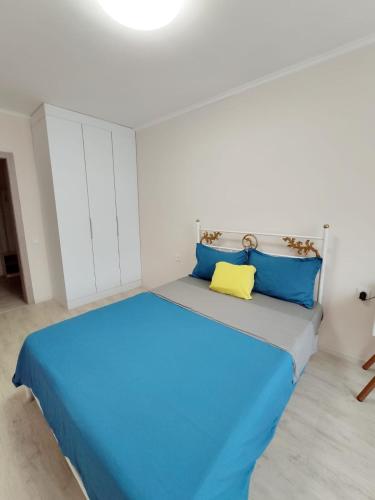 1 dormitorio con 1 cama con almohadas azules y amarillas en Аккуратная 1-комнатная квартира в ЖК Nomad, en Almaty
