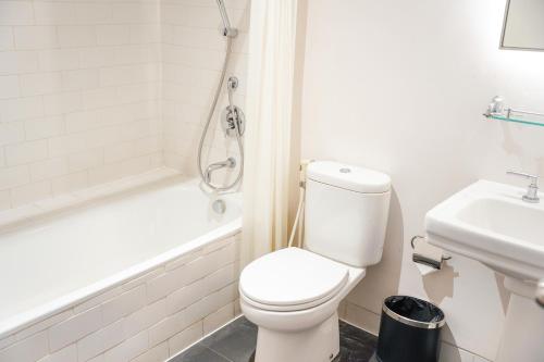a white bathroom with a toilet and a sink at Lemansion Senopati in Jakarta