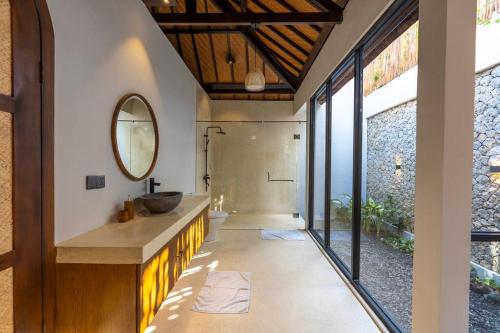 Un baño con lavabo y ducha con espejo. en Green Jimbaran Bay Villa II, en Jimbaran