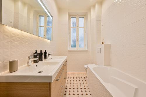 une salle de bain blanche avec une baignoire et un lavabo dans l'établissement Magnifique Appartement de luxe & familia - Paris 16, à Paris