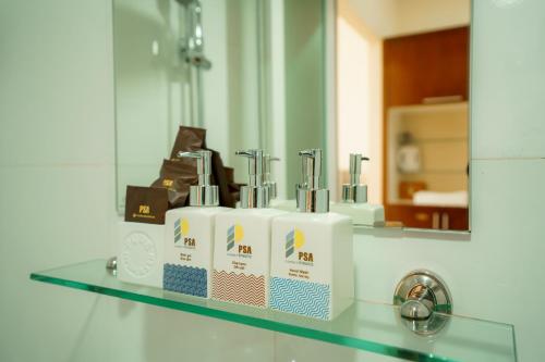 a bathroom counter with three toothbrushes and a mirror at PSA Nghi Sơn Condotel in Thanh Hóa
