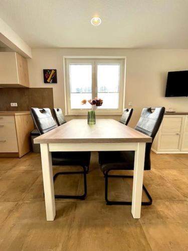 a table with chairs and a vase of flowers on it at Ferienhaus Leni Bettwäsche Handtücher inkl in Hasselfelde