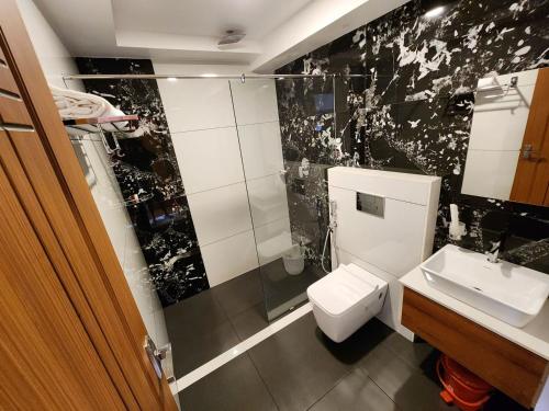 a black and white bathroom with a toilet and a sink at Gee Resort & Heights in Idukki