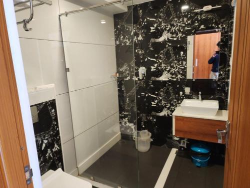 a bathroom with a shower and a sink and a mirror at Gee Resort & Heights in Idukki