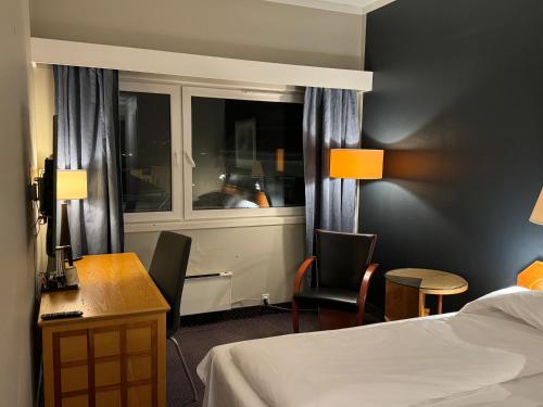 a hotel room with a bed and a desk and a window at Notodden Hotel in Notodden