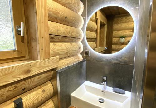 L'OURSBLANC Chalet en rondins في لابريس: حمام مع حوض ومرآة
