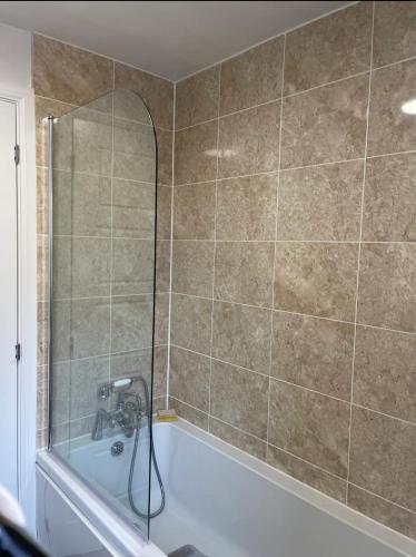 a bathroom with a tub with a shower and a sink at MODERN AND IMMACULATE PRIVATE ROOM IN NUNEATON in Caldecote