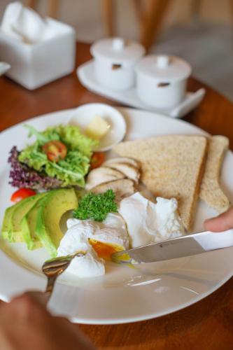 a person holding a plate of food on a table at The Hava Ubud A Pramana Experience in Ubud