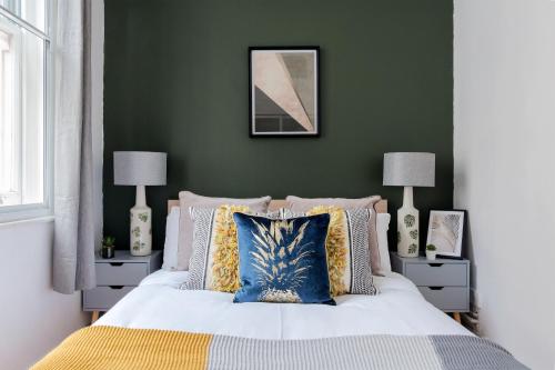a bedroom with green walls and a bed with pillows at The Aldgate Flats in London