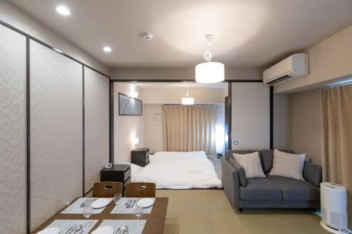 a room with a bed and a couch and a table at H2H Dotonbori in Osaka