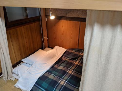 a small bed in a room with a window at Guesthouse Tomaru in Takayama