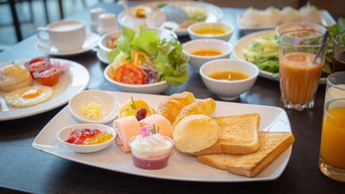 a table with a plate of breakfast foods and drinks at Grand Fortune Hotel Nakhon Si Thammarat in Nakhon Si Thammarat