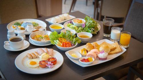 a table with plates of breakfast foods and drinks at Grand Fortune Hotel Nakhon Si Thammarat in Nakhon Si Thammarat