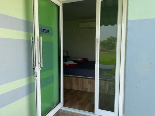 a sliding glass door leading to a room with a bed at Srihome ยายศรีโฮมแอนแคมป์ปิ้ง in Ban Don Tum (1)