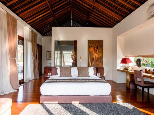 a bedroom with a large bed and a desk at Villa Kalyani in Canggu