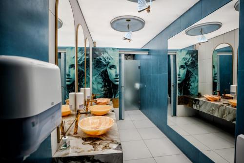 a bathroom with blue walls and sinks and mirrors at Complex Turistic Casa Romaneasca in Călimăneşti