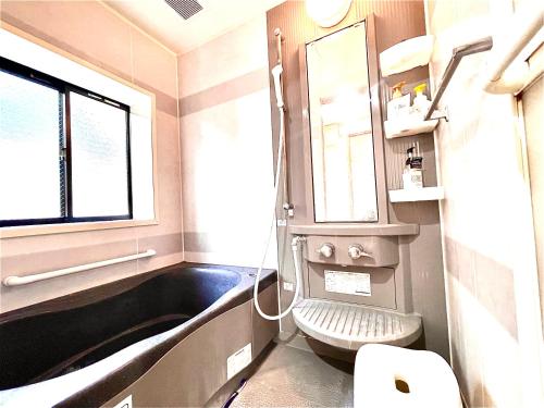 baño con bañera negra y lavamanos en 吉吉の家, en Tokio