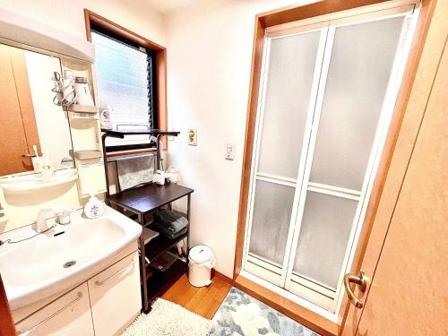 baño con lavabo y puerta de ducha acristalada en 吉吉の家, en Tokio