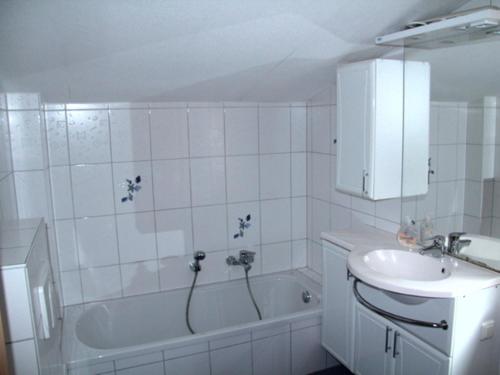 ein weißes Badezimmer mit einem Waschbecken, einer Badewanne und einem Waschbecken in der Unterkunft Ferienhaus Sonnenschein in Baabe in Baabe