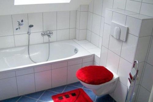 a white bathroom with a red stool on a toilet at Ferienhaus Sonnenschein in Breege in Juliusruh