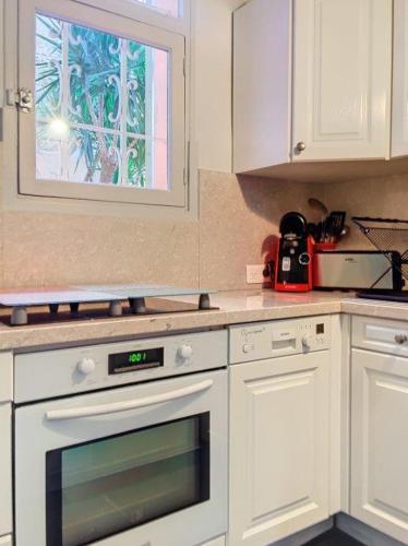 une cuisine avec des armoires blanches et une fenêtre dans l'établissement Charmant studio, à Cannes