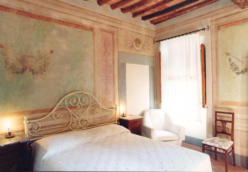 a bedroom with a white bed and a chair at antica casa "le rondini" in Borgo a Buggiano