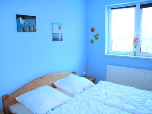 - une chambre bleue avec un lit et 2 oreillers dans l'établissement Ferienwohnung in Glowe auf Rügen, à Glowe
