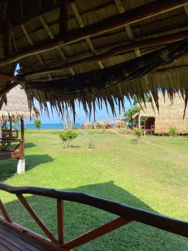 a view of a field of grass with a straw hut at Lanta Marina Resort By Mam&Mod in Ko Lanta