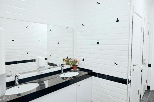 a bathroom with two sinks and white walls at Hotel Kapsula in Astana