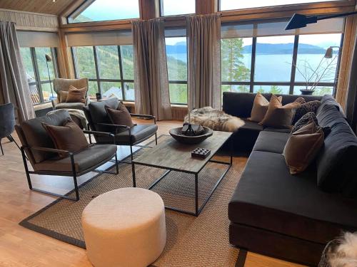 a living room with a couch and chairs and windows at Hjortehytte in Åfarnes