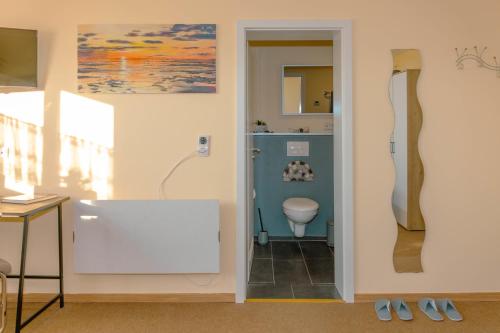 a bathroom with a toilet and paintings on the wall at Sommerzimmer in Homburg