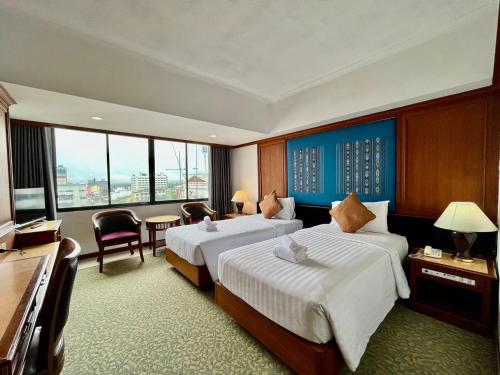 een hotelkamer met 2 bedden en een televisie bij Asian Hotel in Hat Yai