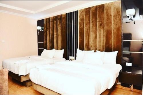 2 Betten in einem Hotelzimmer mit weißer Bettwäsche in der Unterkunft VIEWPOINT HOTEL AND SUITES in Benin-Stadt